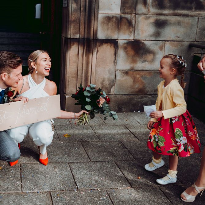 Bride and groom holding a DIY cardboard box 'just married' sign
