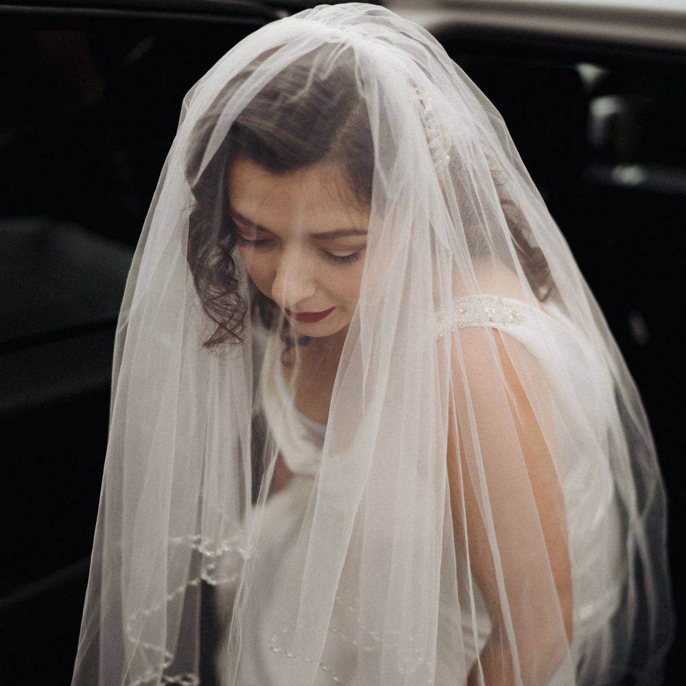 Bride leaves car with veil over her