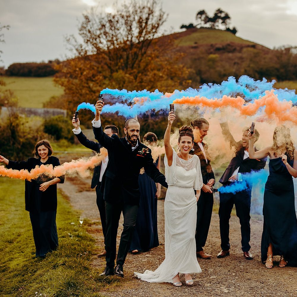 Wedding party with blue & orange smoke bombs outdoors