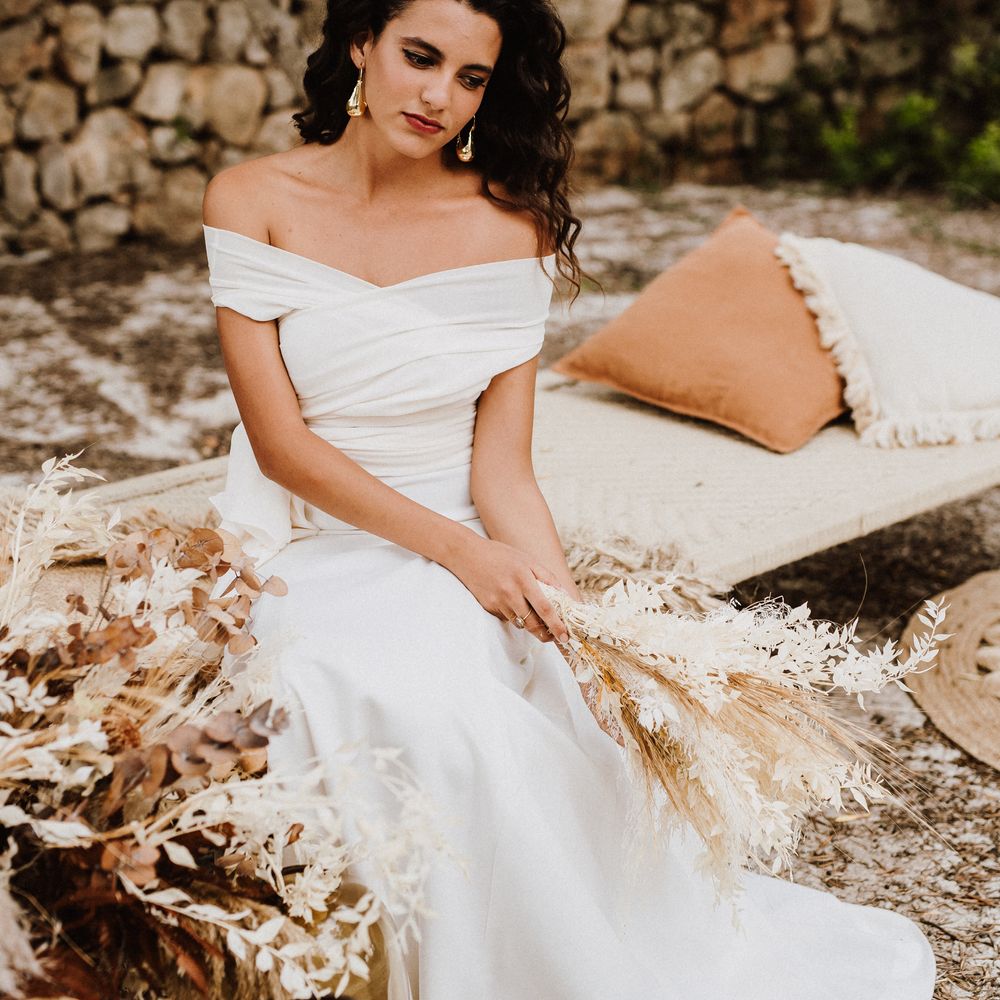 Bride sits outside on outdoor bed wearing boho gown