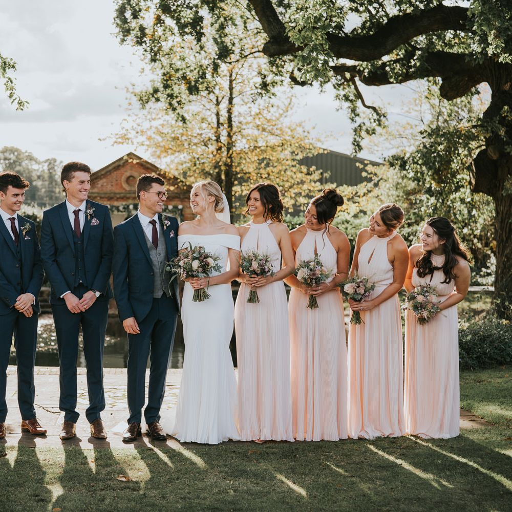 Bride & groom stand with their wedding party at either side of them
