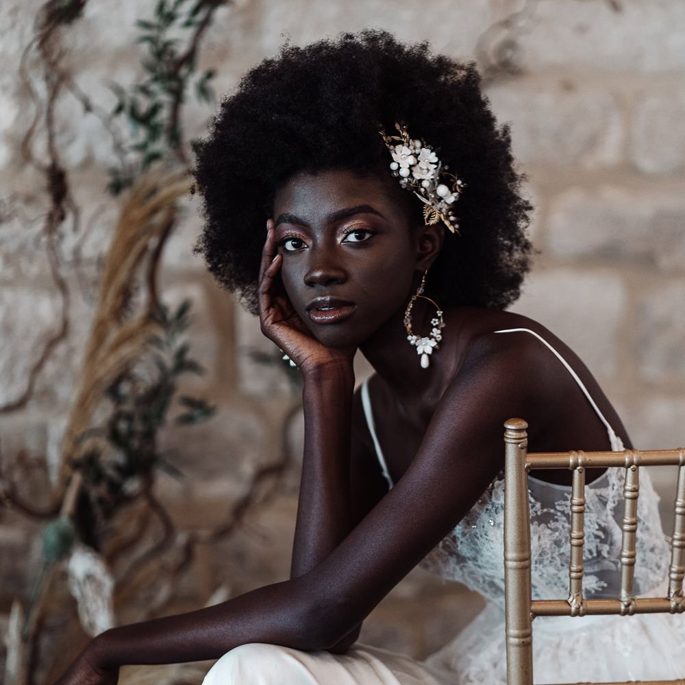 Beautiful Black bride with afro hair, hair accessory and earrings with shimmering gold eyeshadow and lipgloss 