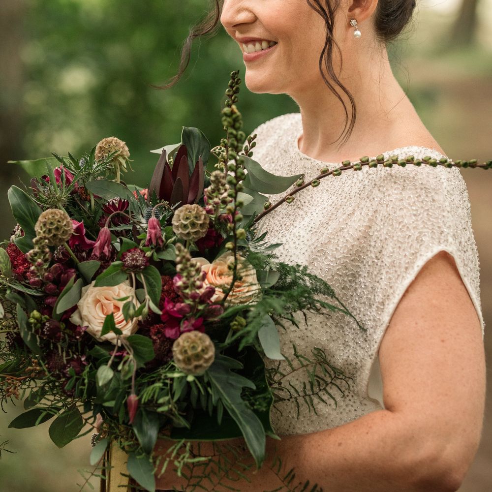 Bride carries floral bouquet and wears wedding band in her hair