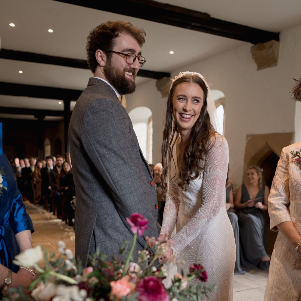 Bride and groom holding hands - bride wears beaded long sleeved bridal gown