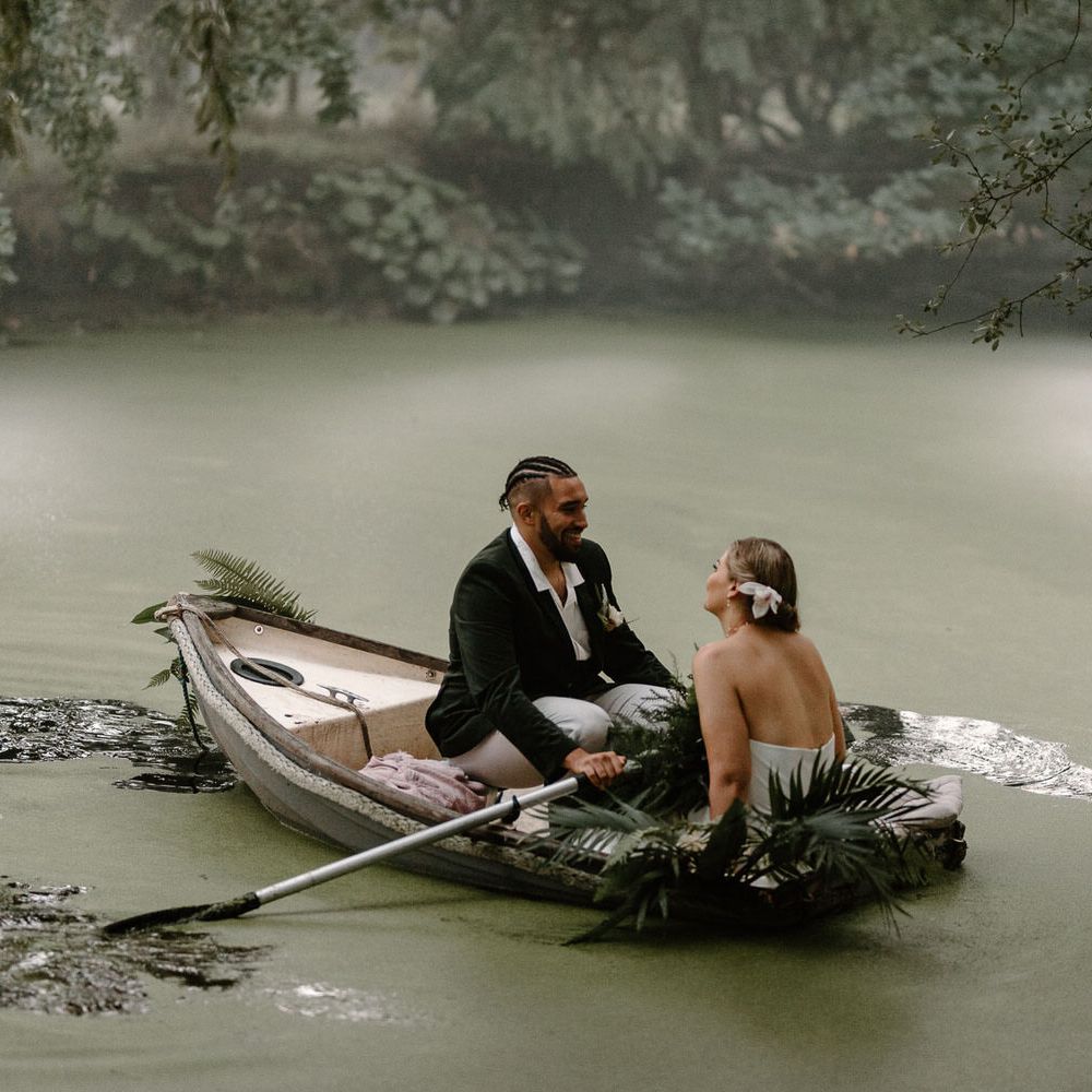 Bride and groom sailing in a rowboat on a green algae covered lake