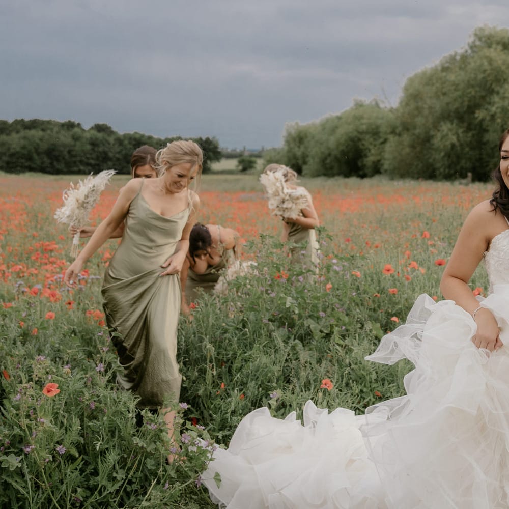 Beautiful bride walking through a poppy field holding her fishtail skirt up 