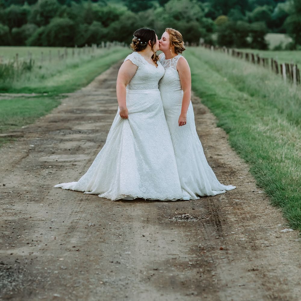Lesbian brides stand together in the countryside for Park Farm wedding