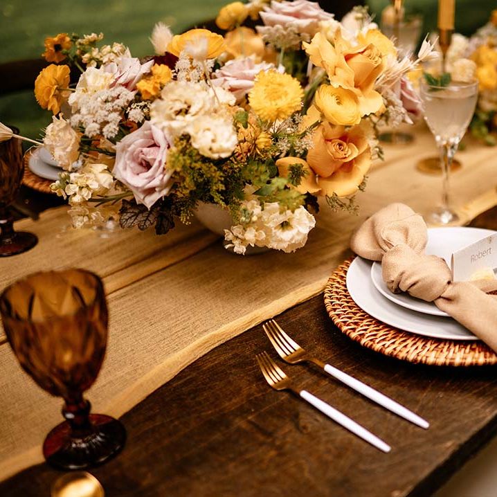 Place setting with wicker place matt and yellow flower floral centrepiece 