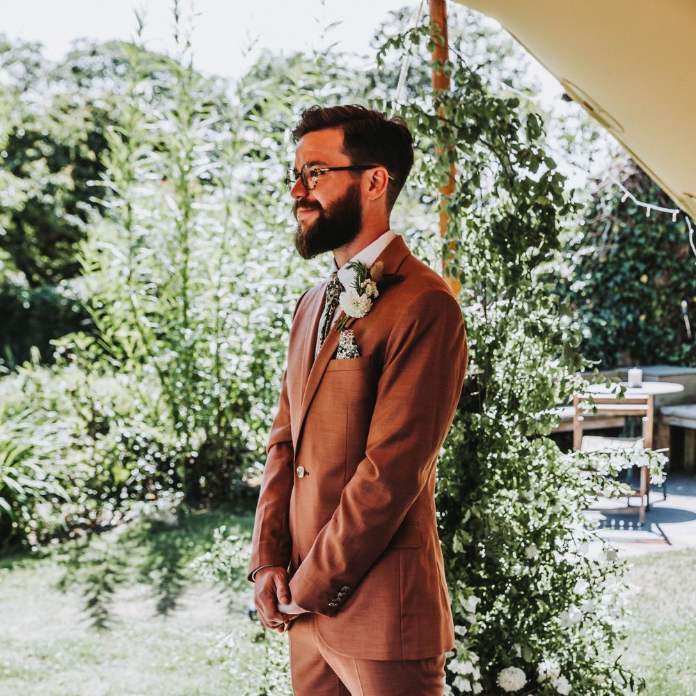 Groom awaits bride during wedding ceremony whilst wearing Topman suit in deep coral colour