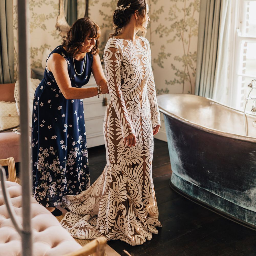 Bride in Boho long lace wedding dress getting ready with curled hair up bridal hair style 