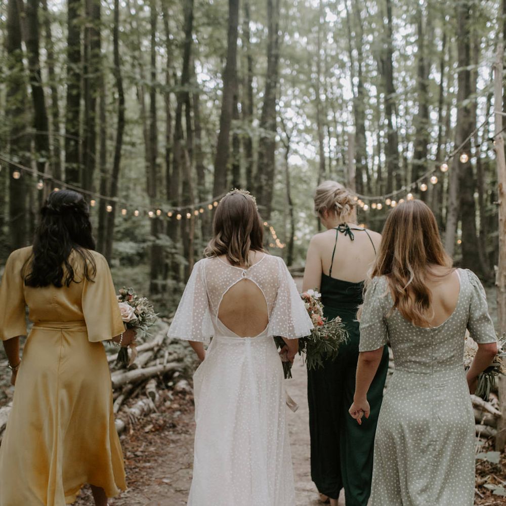 Bride walks with her wedding party as she wears wedding gown with V shaped back 