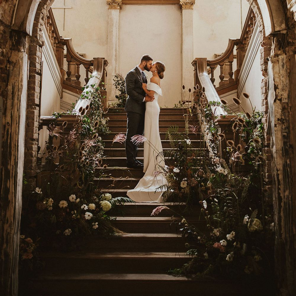 Bride & groom kiss on staircase on their wedding day 