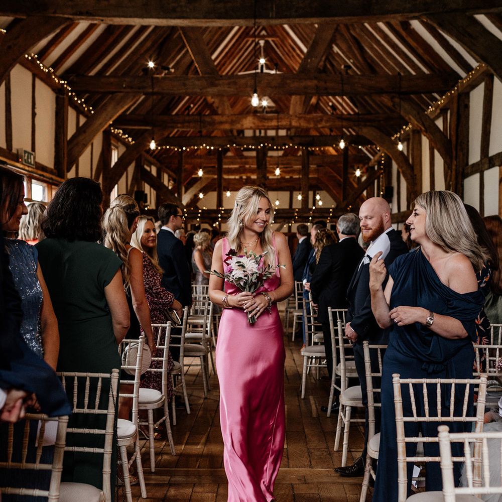 Bridesmaid walking down the aisle in a pink satin bridesmaid dress