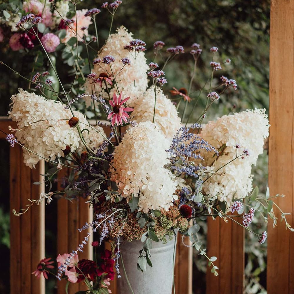 White, purple and pink wedding flowers for decor in metal bucket 