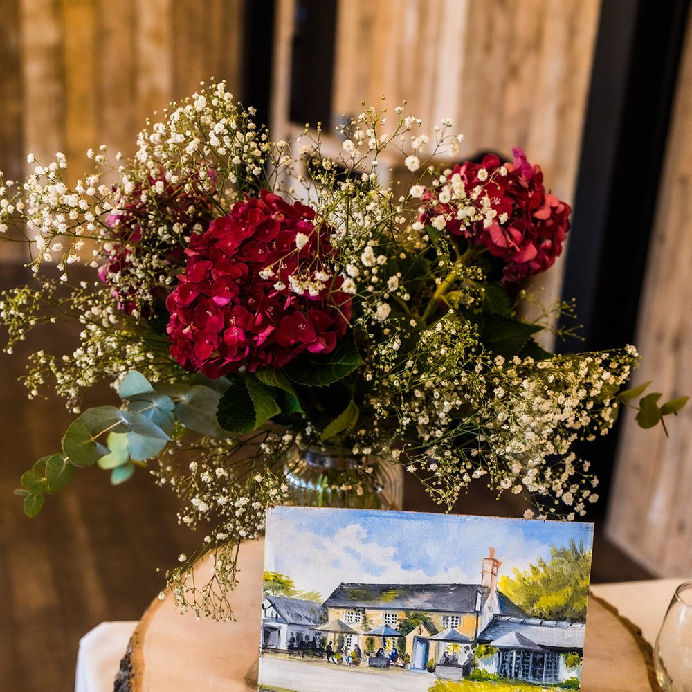 Tree trunk stand with hand painted landscape with bunch of deep red hydrangeas and gypsophila