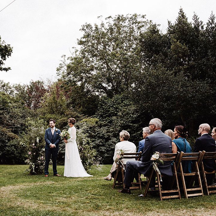 Bride and groom stand at the altar for outdoor wedding ceremony at Treseren with two flower columns for altar decor