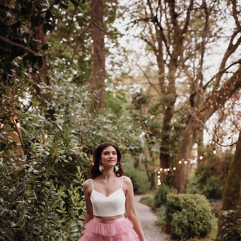 Bride in a pink ruffled wedding skirt with front split and white crop top in the gardens at Ballykealey House wedding venue in Co. Carlow, Ireland