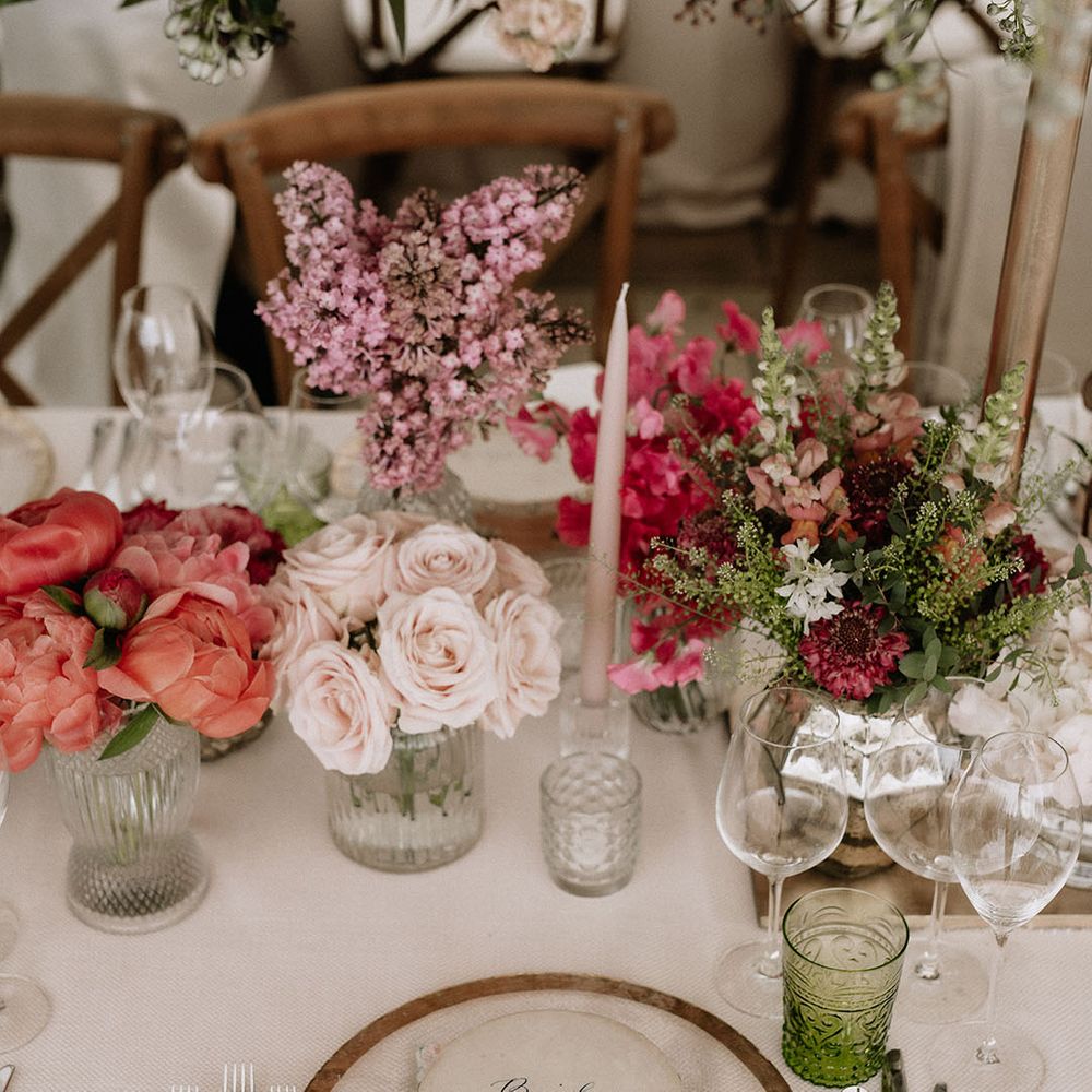 Table setting with green coloured glassware, tambourine name place with pink bow on top of embroidered personalised napkins and pink flower display 