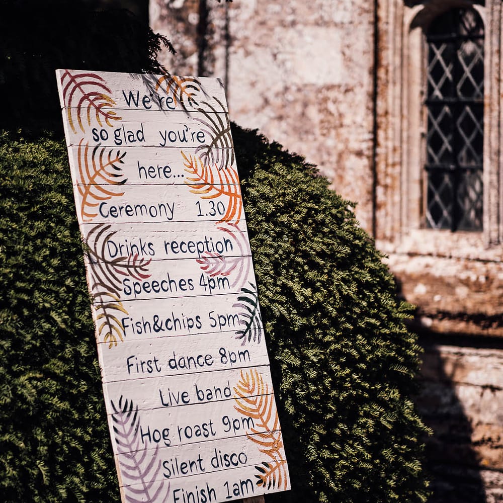 White painted wooden pallet order of the day wedding sign with colourful patterns 
