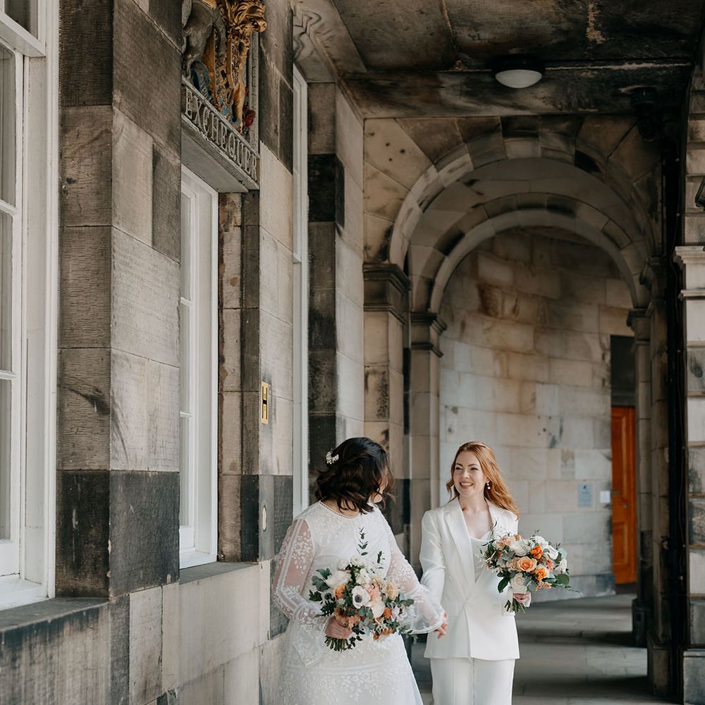 Bride leads her bride whilst holding her hand on their wedding day