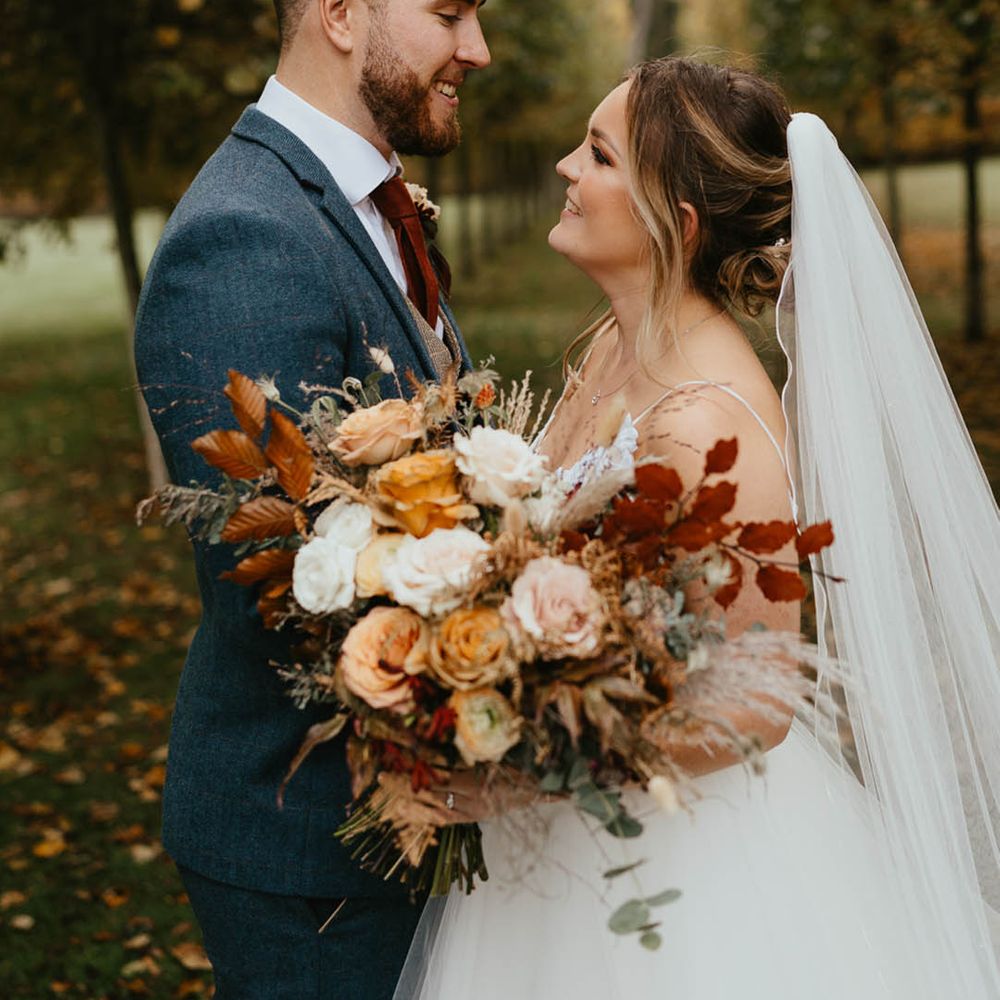 Bride and groom gaze and smile at each other as they pose for couple portraits 