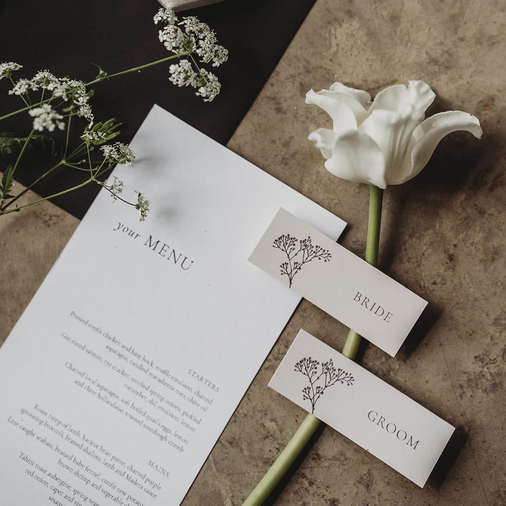Wedding menu with place names, white flowers and a velvet ring box for the bride's wedding and engagement ring 