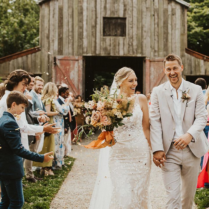 Bride and groom laugh together as they have their confetti moment exiting Nancarrow Farm wedding venue 