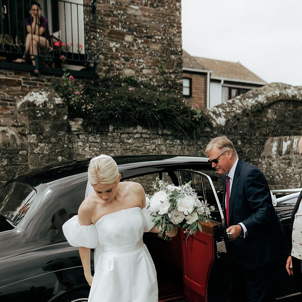 Bride wears Jesus Peiro wedding dress with puffed sleeves and holding bridal bouquet 