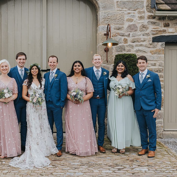 wedding party in pastel pink and blue dresses and groomsmen in navy blue suits 