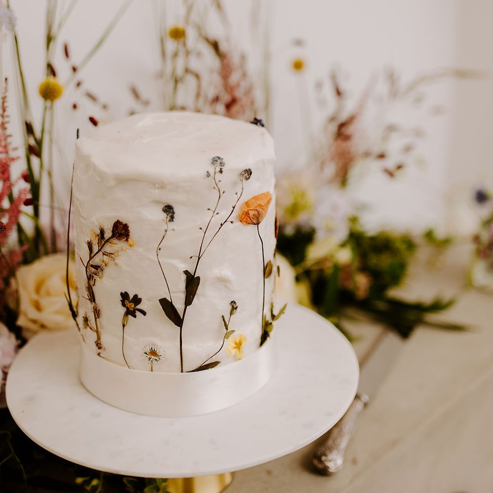 Single tier white iced rustic wedding cake with pressed wildflowers 