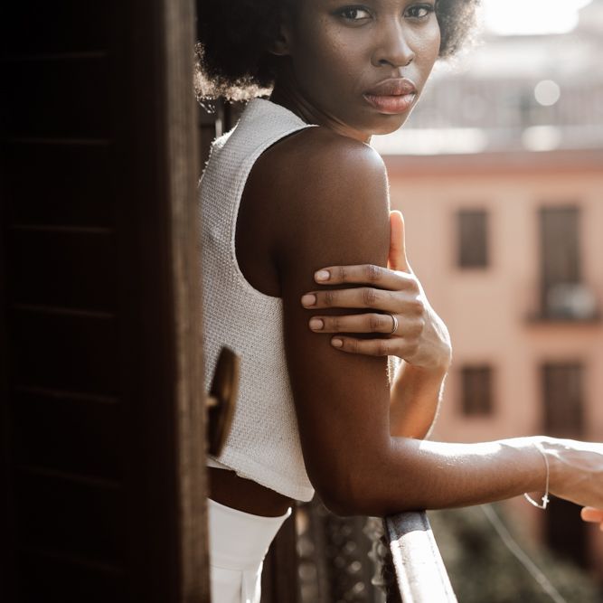 Bride stood on balcony in white trousers and top 