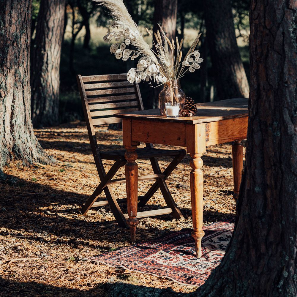 Wooden table outdoors with vases filled with dried flowers
