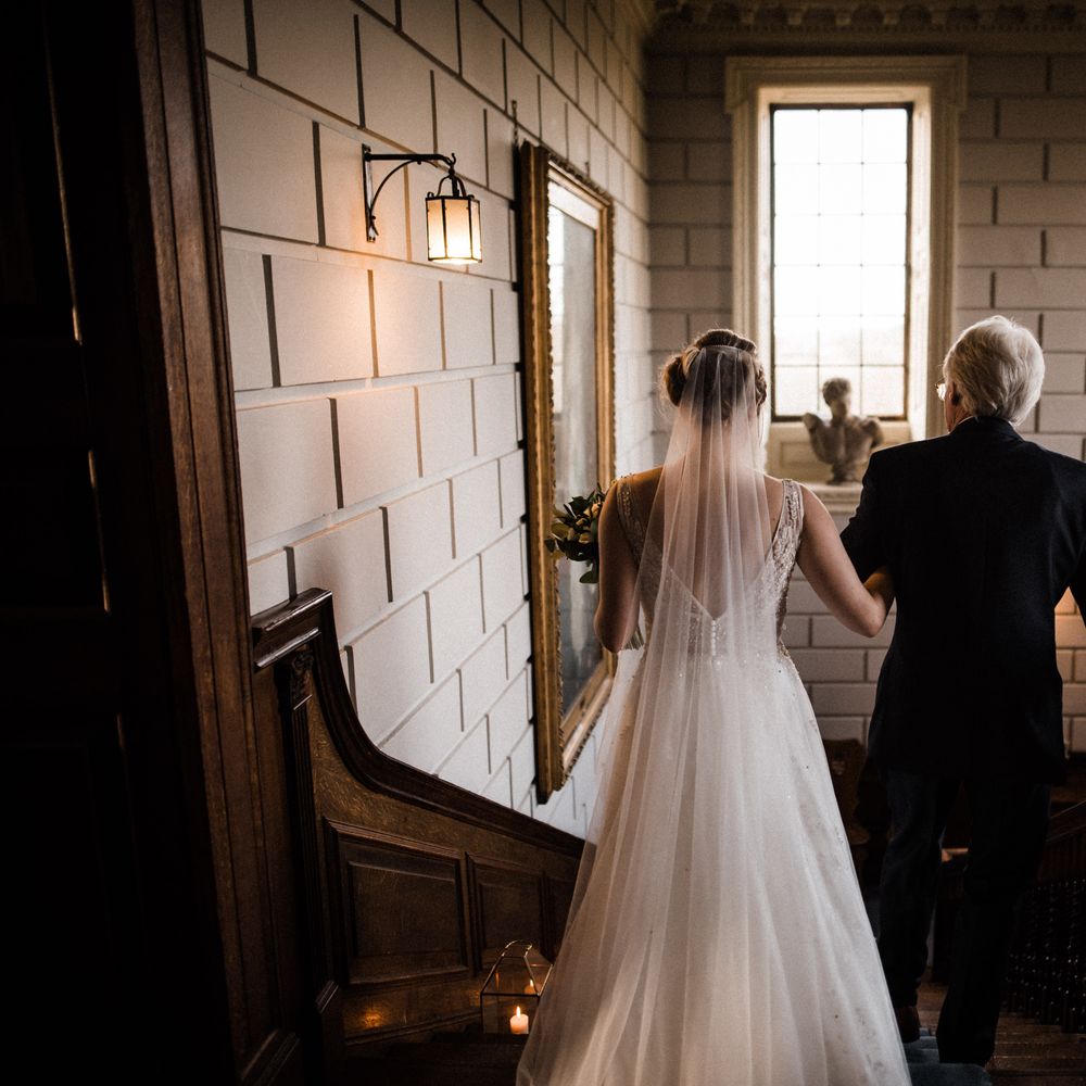 Bride walks down the stairs with her father before ceremony