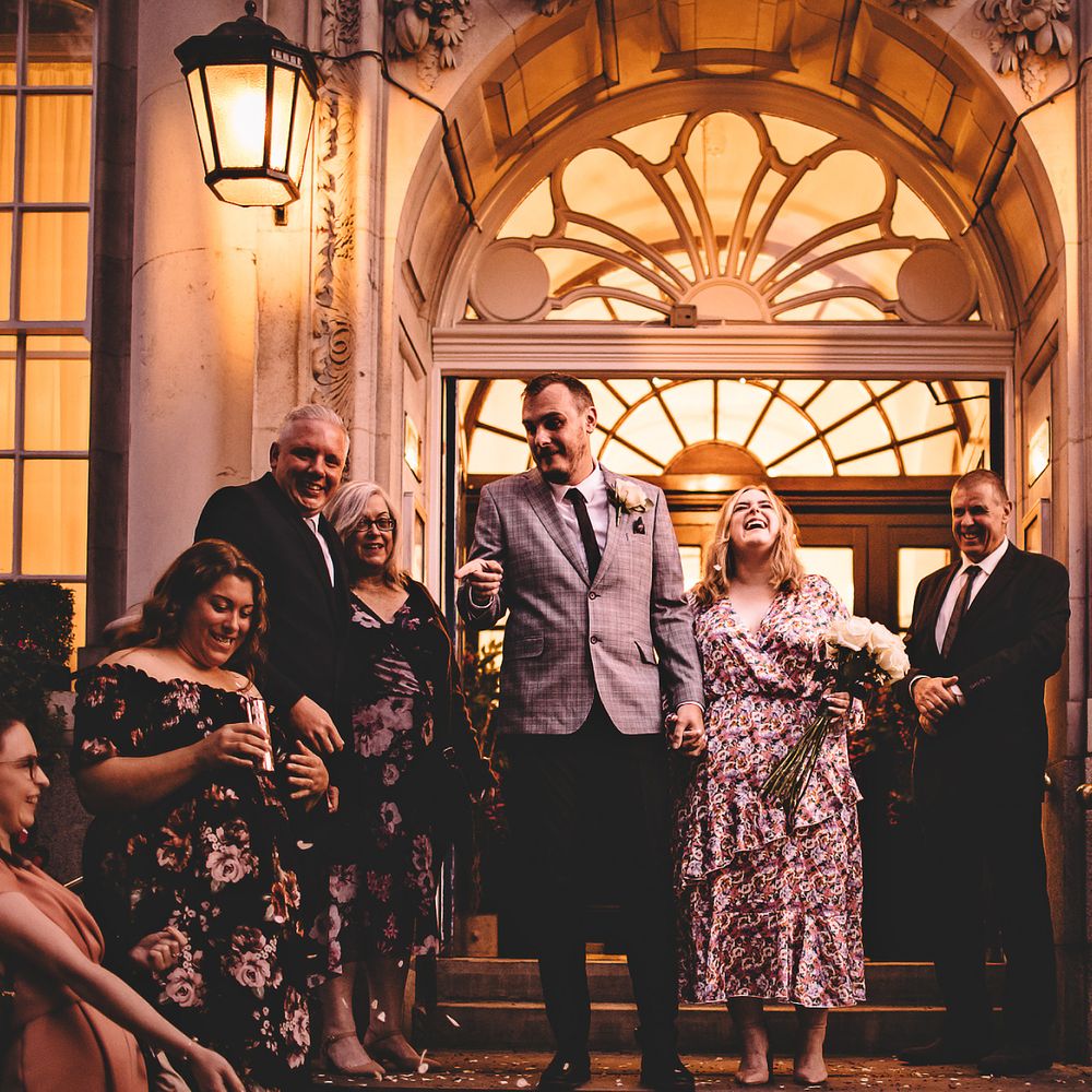 Bride laughs as she holds hands with her groom on steps after marrying at Chelsea Old Town Hall