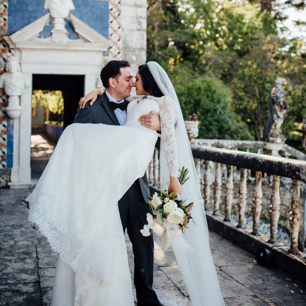 Groom carries his bride outdoors as her dress and veil fall to the floor