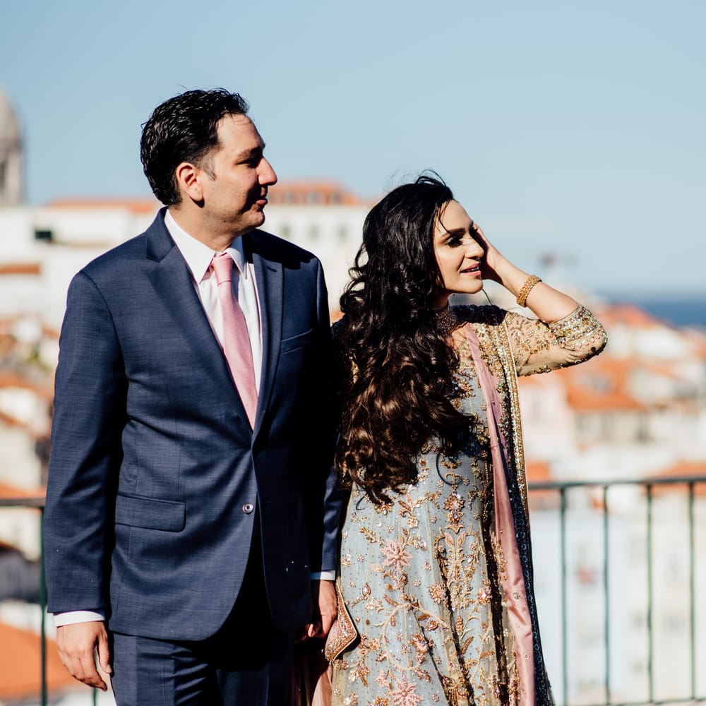 Bride & groom look across Lisbon, as groom wears blue suit with pink tie 
