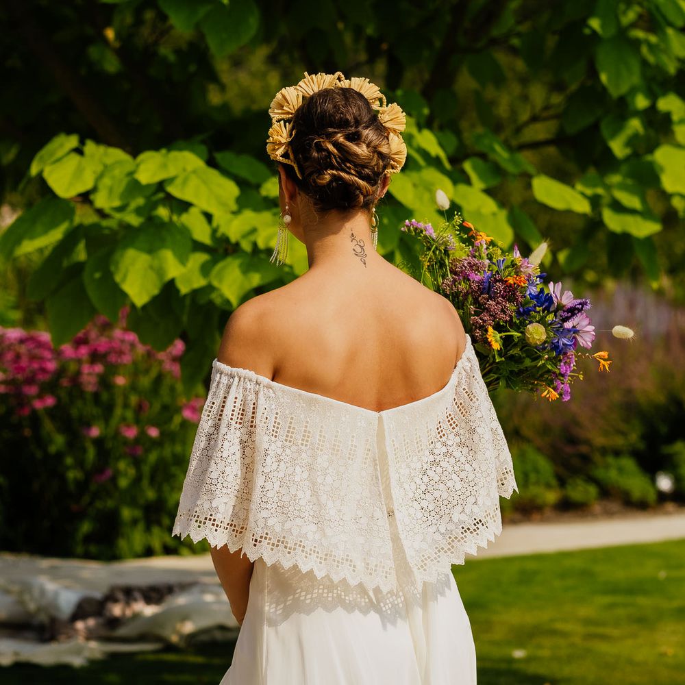 Bride in a strapless wedding dress with lace overlay holding a wildflower bouquet and wearing a yellow appliqué headband 