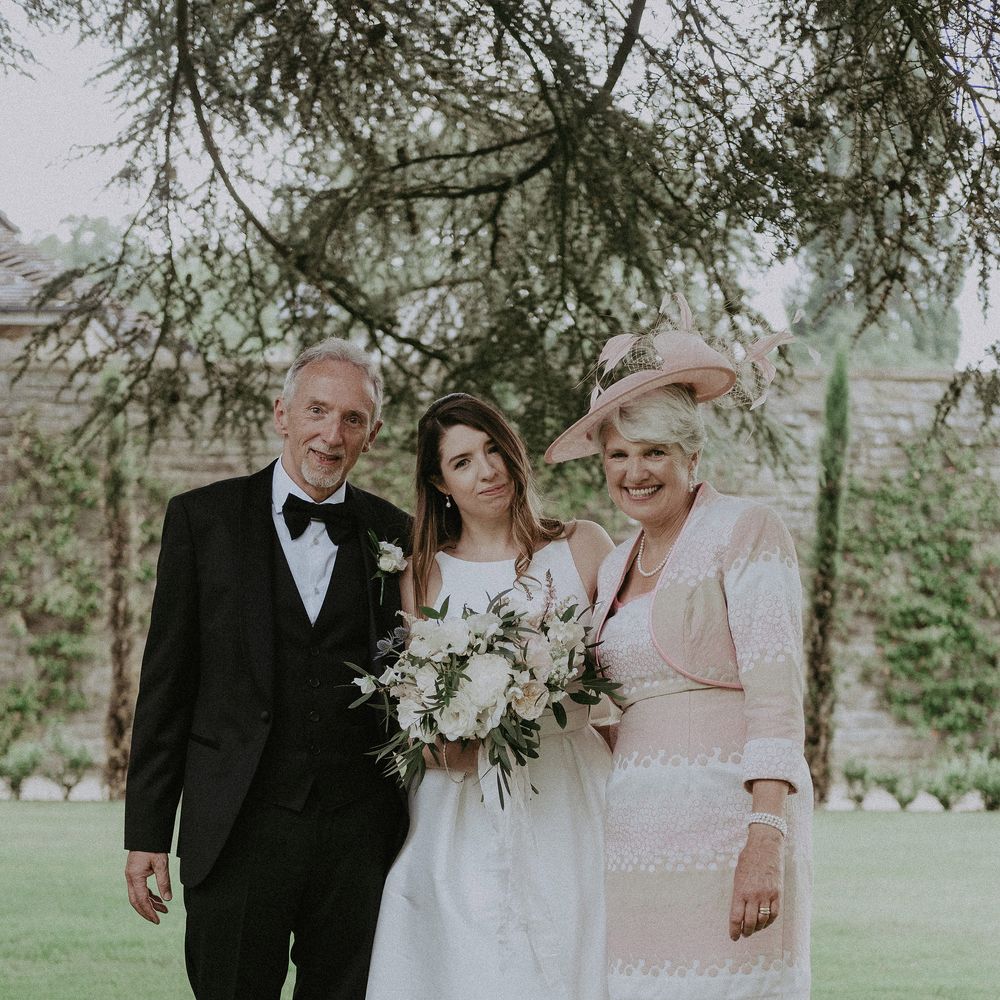 Bride stands with her mother and father of the day of her wedding whilst wearing Jesus Peiro dress
