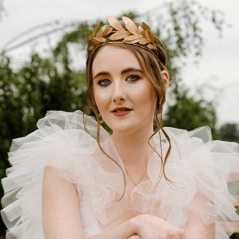 Beautiful bride with natural makeup in a tulle wedding dress wearing a gold laurel crown headdress