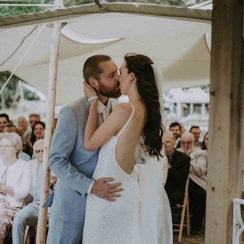 Bride and groom kiss at outdoor wedding ceremony