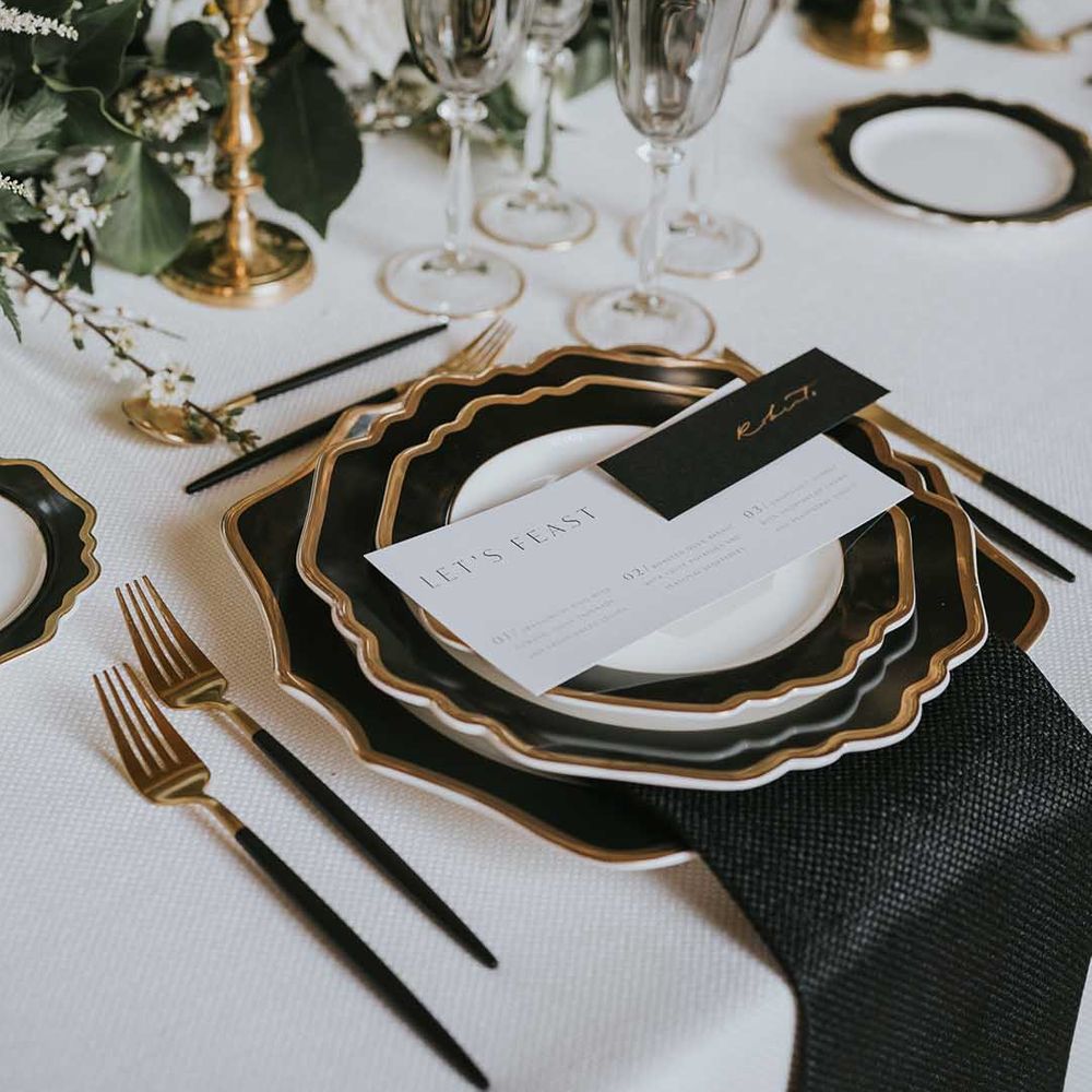 black, white and gold wedding place setting with gold cutlery, black napkin and menu card