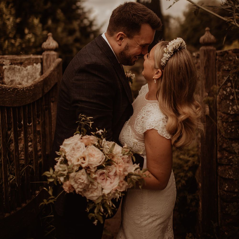 Bride in a lace cap sleeve wedding dress wearing a flower crown and holding a romantic wedding bouquet 