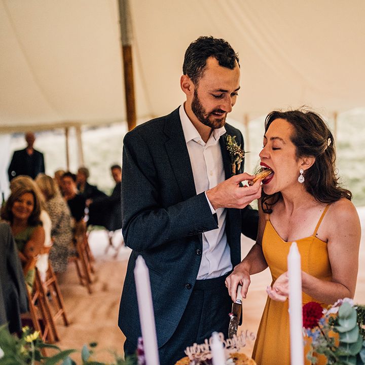 Groom feeds bride wedding cake at reception