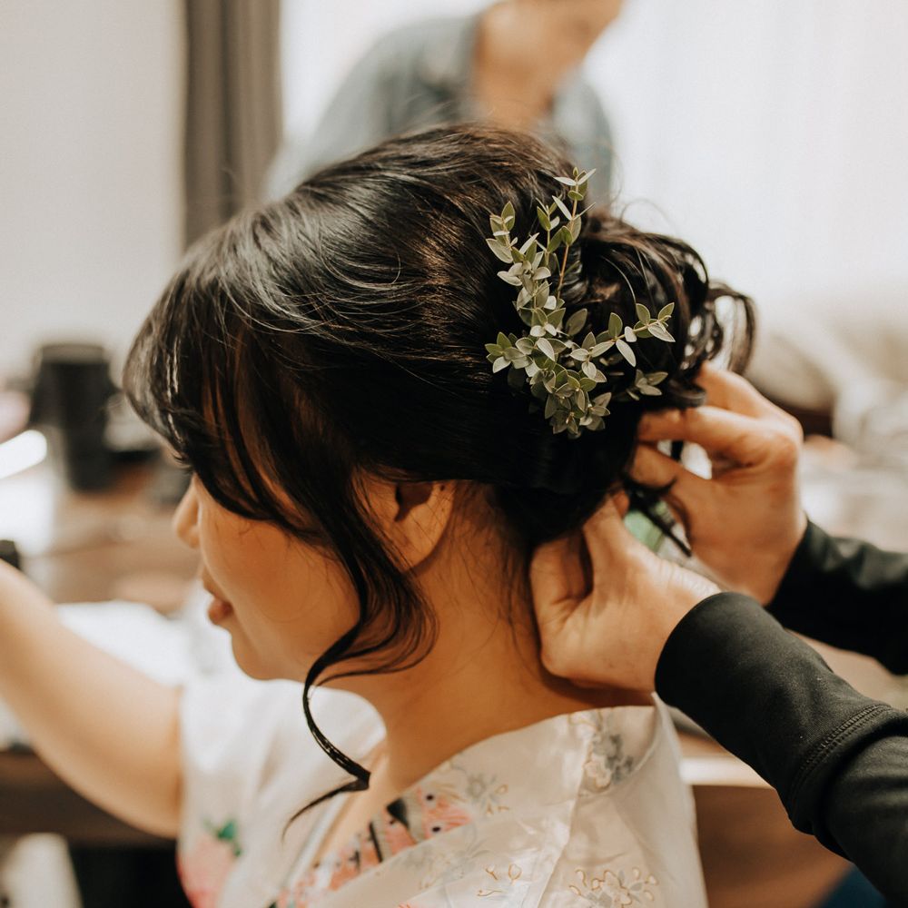 Bride with curled wedding up do has foliage hair decorations pinned 