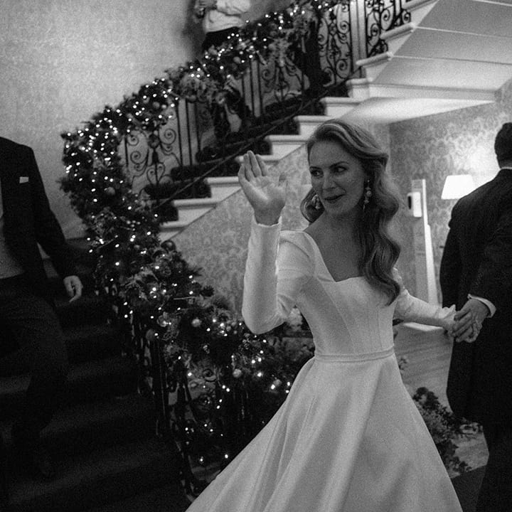 Bride in white long sleeved wedding dress with square neck and full skirt 