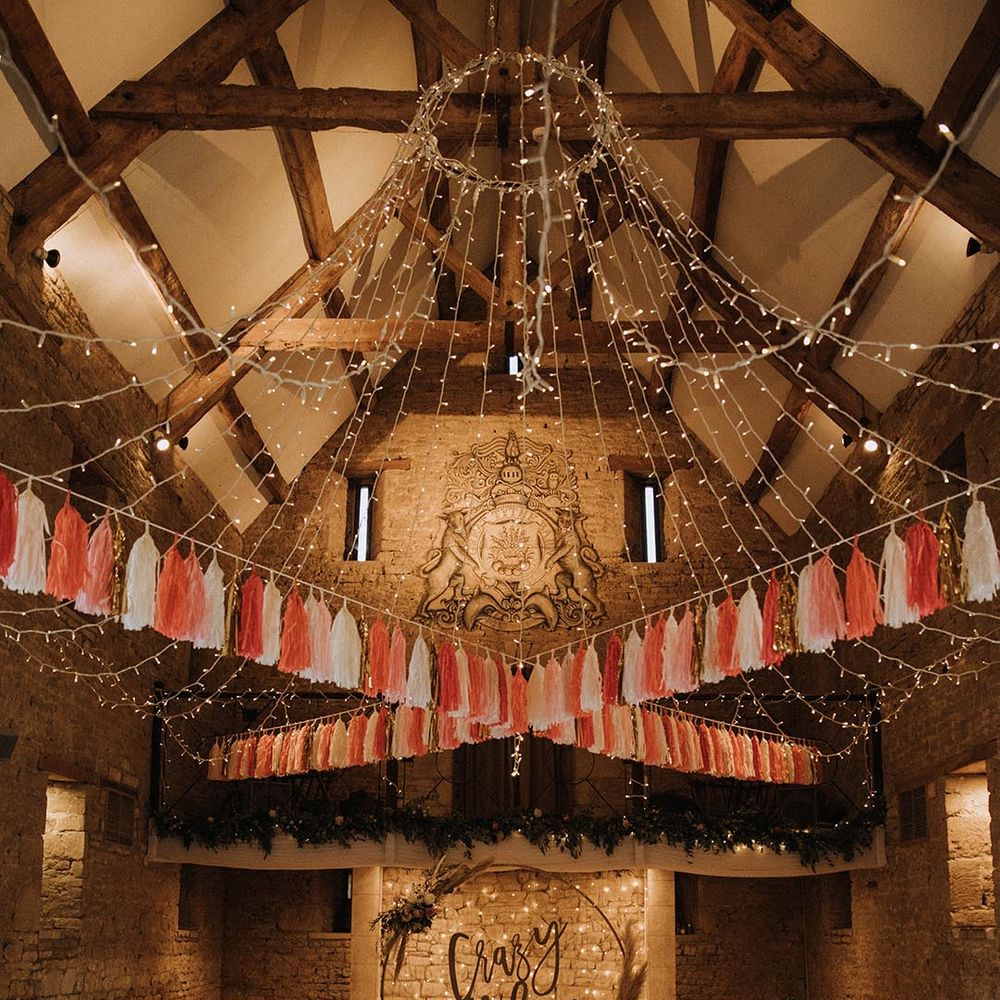The Great The Barn wedding dress with tassel bunting, fairy lights and Crazy In Love top table backdrop sign 