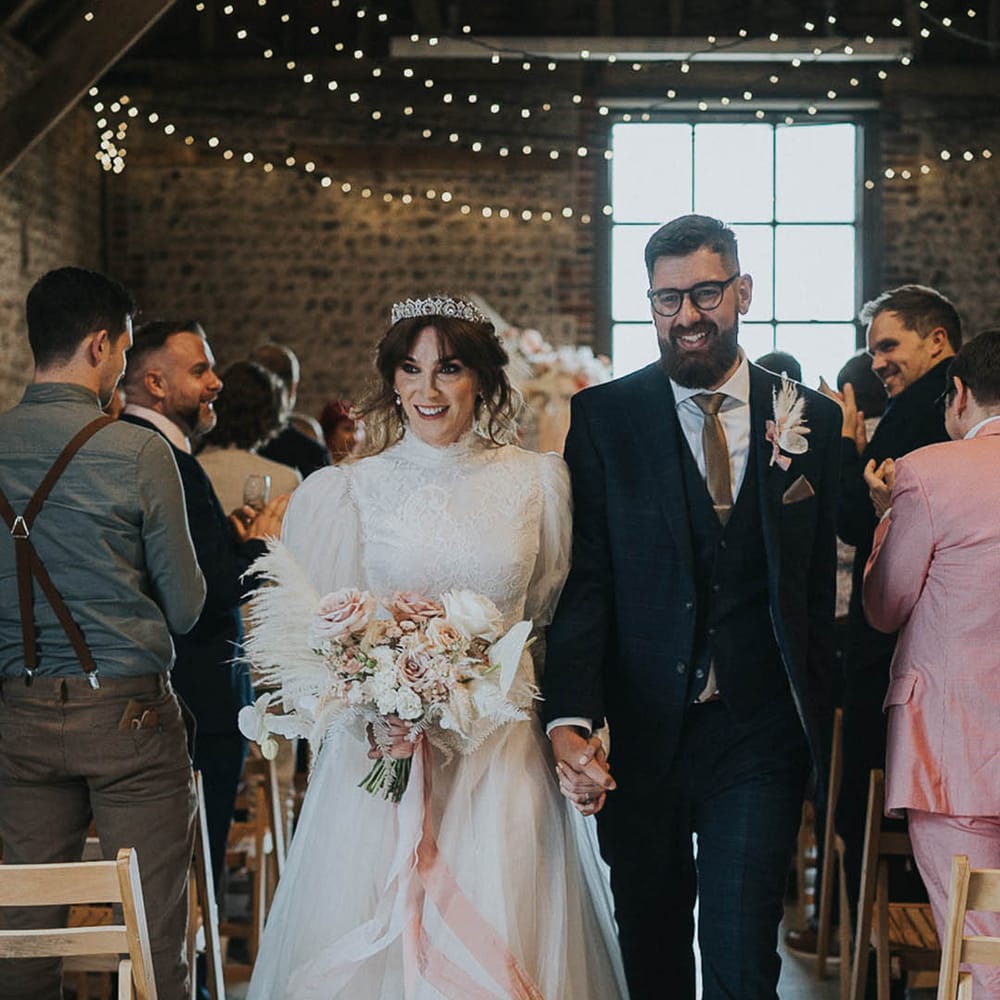 Couple walk down the aisle after hand fasting LGBTQI+ wedding ceremony 