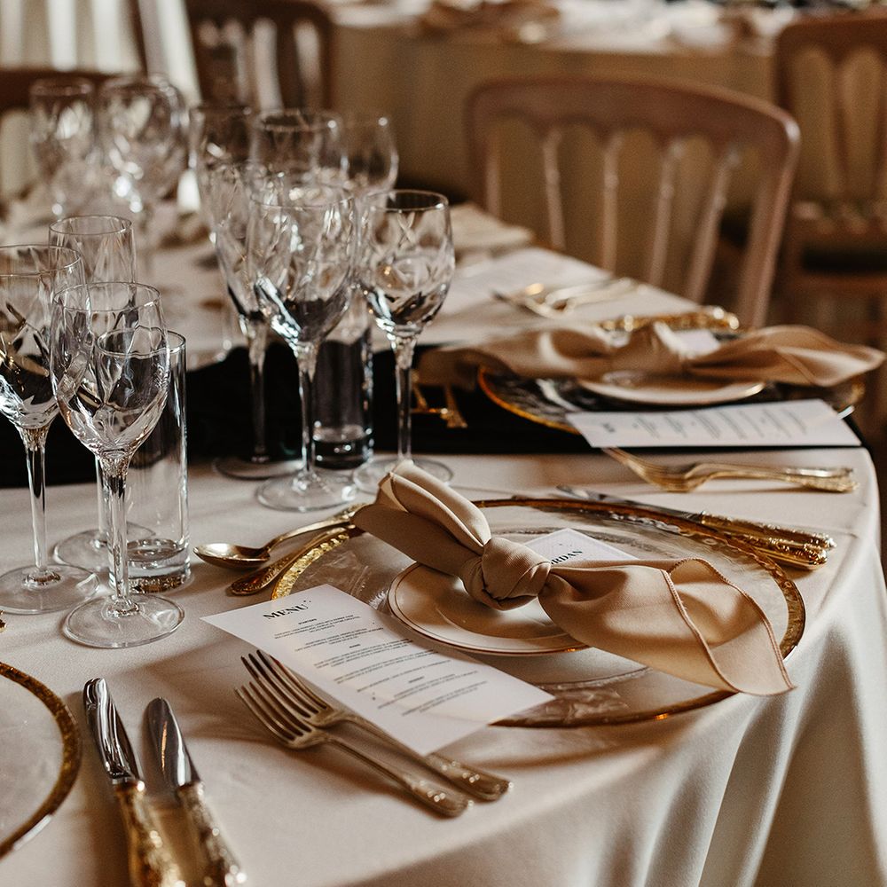 Gold cutlery and plating with white tablecloth and black candles for autumn witchy style wedding at Drumtochty Castle