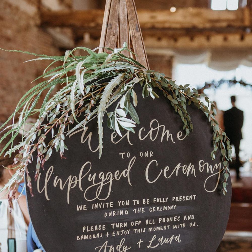 Black rounded unplugged wedding ceremony with green foliage 