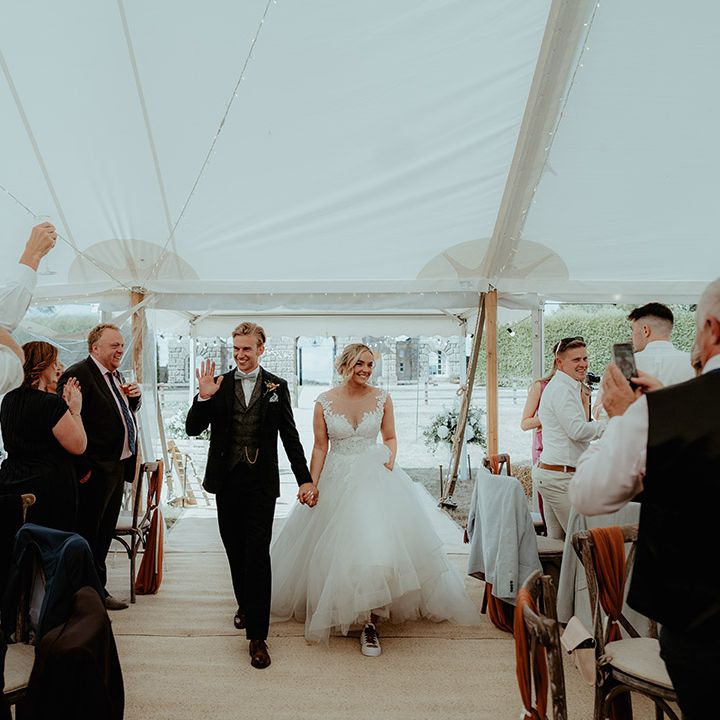 Bride and groom enter their marquee wedding reception at the Badminton Estate